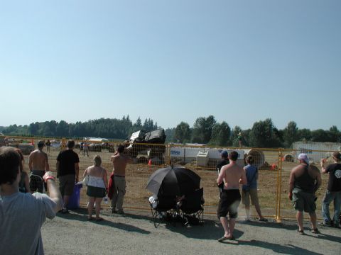 Black SUV flipped on its side at an outdoor event with spectators watching.