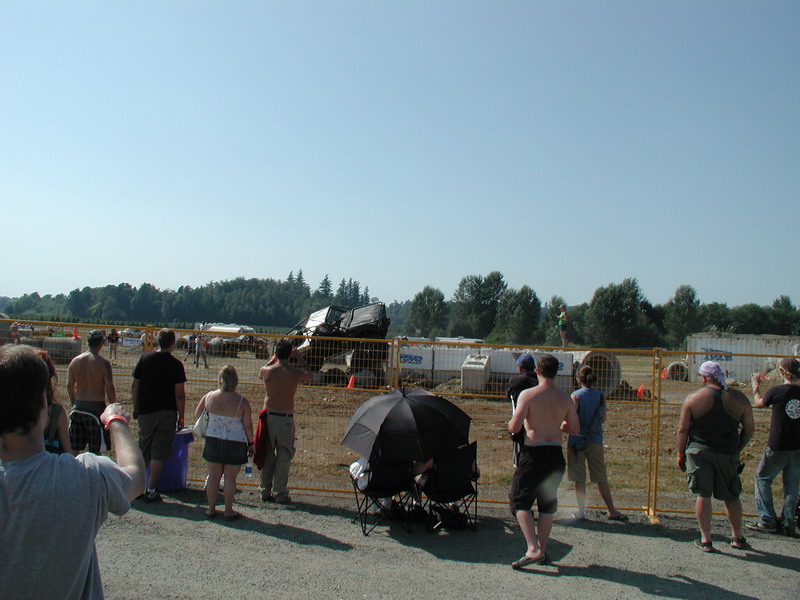 Black SUV flipped on its side at an outdoor event with spectators watching.