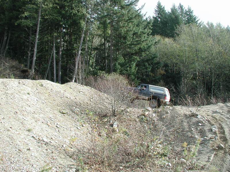 Dark SUV driving up a rocky hill in a forest.