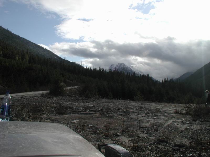 Front view of a vehicle parked on rocky ground with mountains in the background.
