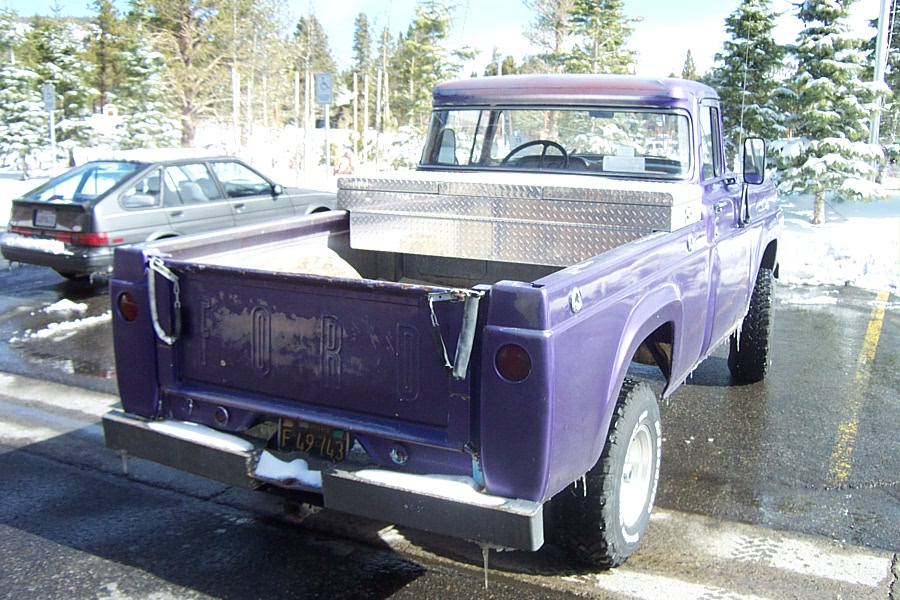 1959 Ford F-100 pickup truck, rear view, with another car parked behind it in a snowy lot