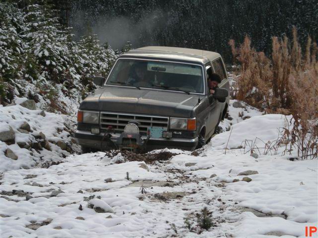 Dark SUV stuck in snow on a dirt road with winch.