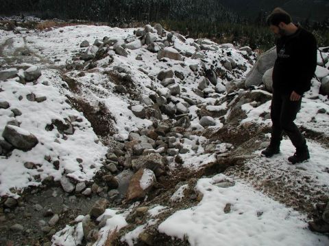 1985 Ford Bronco - A man walks through a rocky, snow-covered landscape with a small stream running through it.