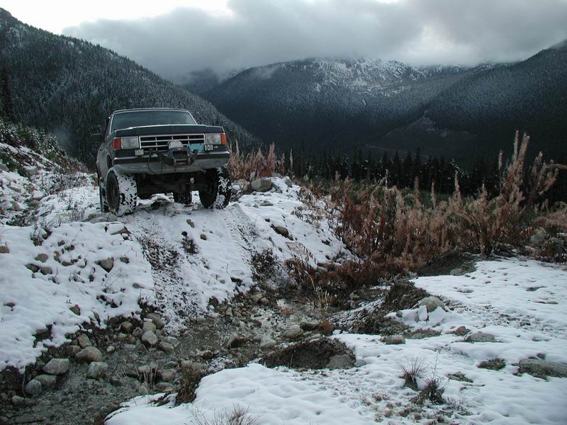 Lifted Ford Bronco on a snowy mountain trail.