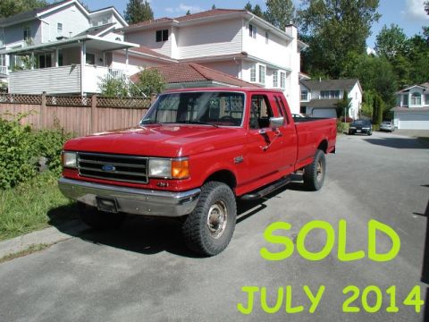 1990 Ford F-250 - A red 1990 Ford F-250 pickup truck is parked in a driveway in front of houses. The truck has a chrome bumper and off-road tires.