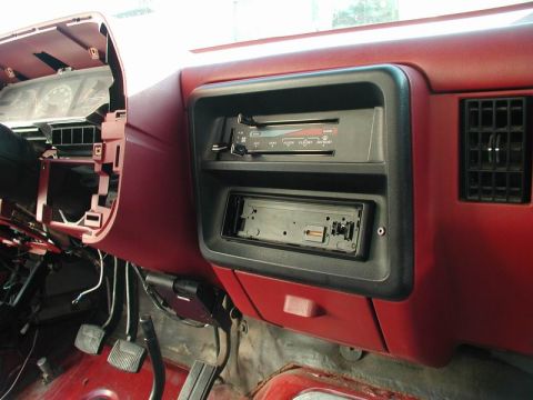 1990 Ford F-250 - The interior of a vehicle's dashboard shows a red dashboard with a black radio bezel. The dashboard has two radio slots, one with a radio i…