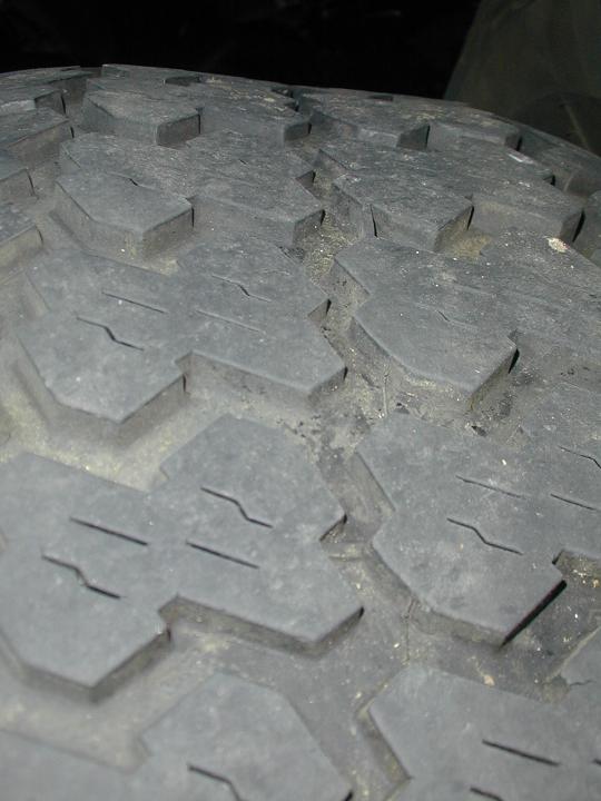 Tire tread with deep lugs and sipes. Some dirt is visible in the grooves