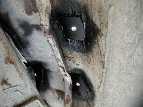 1990 Ford F-250 - Close-up view of the underside of a vehicle, showing two black metal plates with visible bolt holes, likely reinforcement or repair patches…