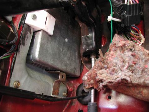 1990 Ford F-250 - A close-up view of the underside of a vehicle's dashboard, showing wiring harnesses, a metal component, and a white plastic bracket. The re…