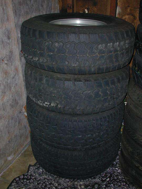 Stack of four off-road tires with silver rims