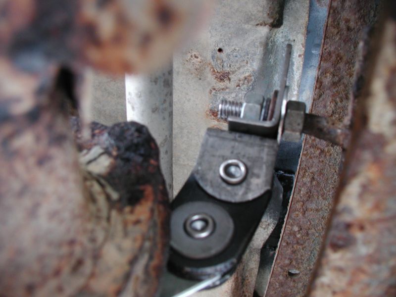 Close-up of a metal bracket with bolts on a rusty vehicle frame.