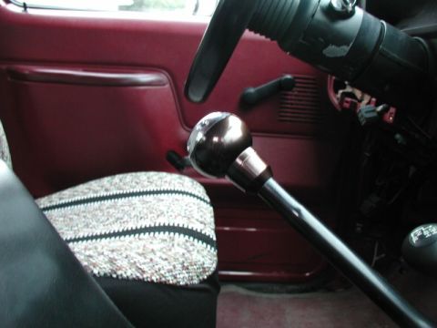 1990 Ford F-250 - The interior of a classic truck shows a close-up of the gear shifter with a shiny, metallic knob. The driver's side door panel and a patter…