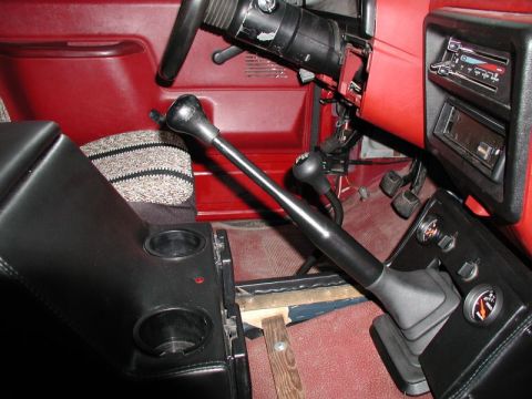 1990 Ford F-250 - The interior of a pickup truck shows a close-up of the center console area with two gear shifters, cup holders, and part of the dashboard w…