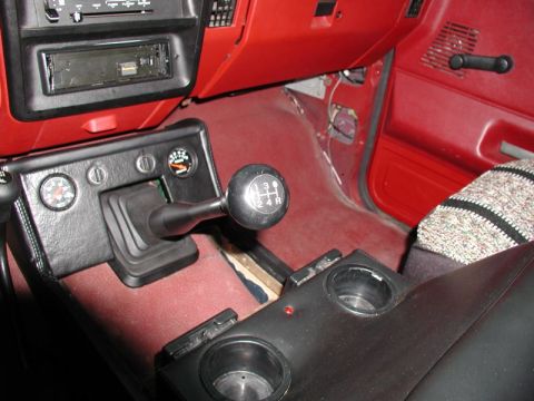 1990 Ford F-250 - The interior of a vintage Ford truck features a red dashboard and carpet, with a manual transmission shifter and two gauges visible on the…