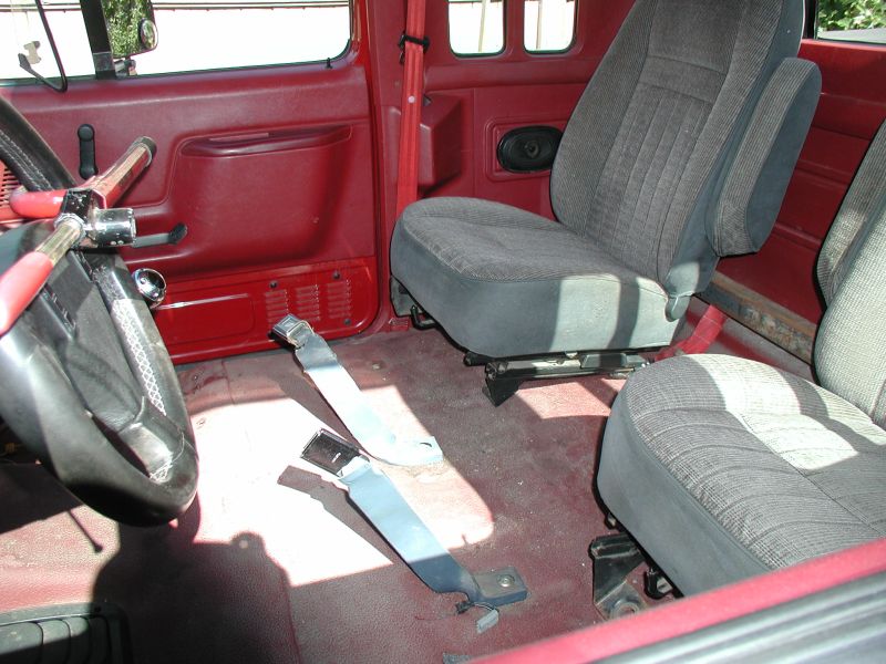 Interior of a red Ford F-250 pickup truck showing driver's side door, steering wheel, and front seats.