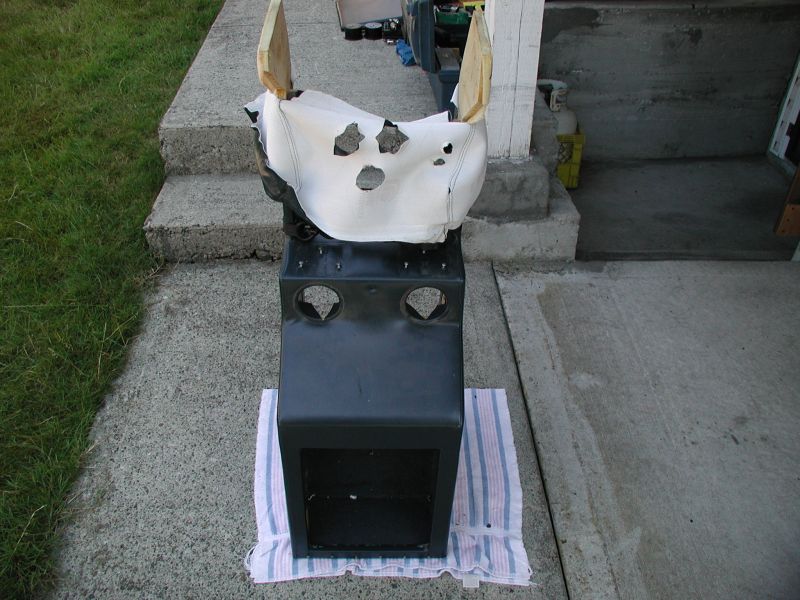 Dark console unit with circular cutouts on top and open bottom, on a striped towel.