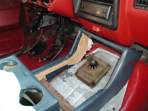 1990 Ford F-250 - The interior of a vehicle shows a manual transmission shifter and part of the center console with cup holders. The dashboard and floor are…