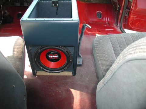 1990 Ford F-250 - The interior of a red Ford F-250 pickup truck shows a custom center console with a blue upholstered storage compartment and a red Sony Xplo…