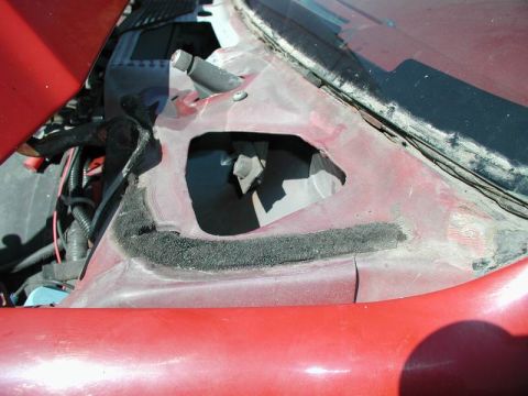 1990 Ford F-250 - This is a close-up view of the cowl area of a red vehicle, showing a large cutout in the metal with black foam insulation around the edges.…