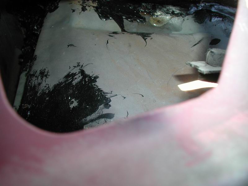 Interior of vehicle cargo area with black tar-like substance and a bolt.