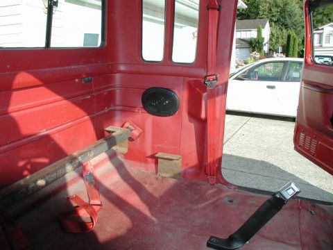 1990 Ford F-250 - Interior view of a red Ford F-250 pickup truck, showing the rear seating area with exposed floor and a speaker mounted on the side panel. A…