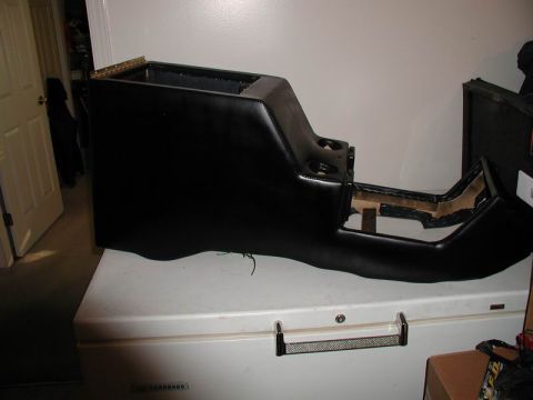 1990 Ford F-250 - A black custom center console with cup holders is shown resting on top of a white chest freezer. The console appears to be upholstered in b…