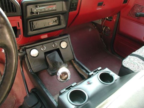 1990 Ford F-250 - The interior of a classic Ford pickup truck shows a custom center console with a shifter, cup holders, and auxiliary gauges. The dashboard…