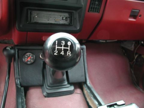 1990 Ford F-250 - The interior of a vintage Ford pickup truck shows a manual transmission shifter with a chrome knob displaying the gear pattern. To the left…