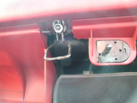 1990 Ford F-250 - This is a close-up view of the interior of a red Ford F-250, showing the latch mechanism and a part of the glove box door. The latch is a m…