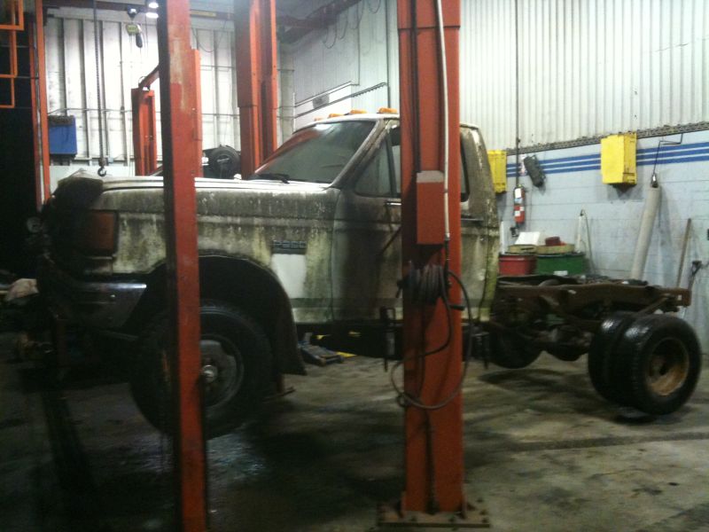 1990 Ford F-250 chassis on a lift in a garage.