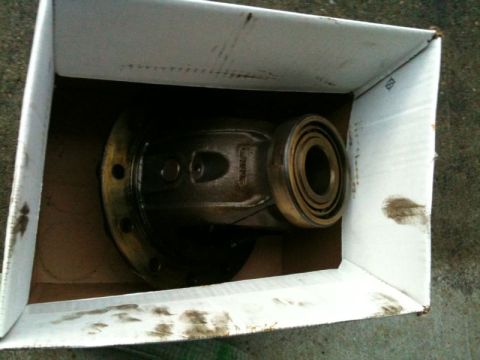 1990 Ford F-250 - A differential housing with bearings is shown inside a cardboard box. The box and the differential are dirty, suggesting it is a used part.