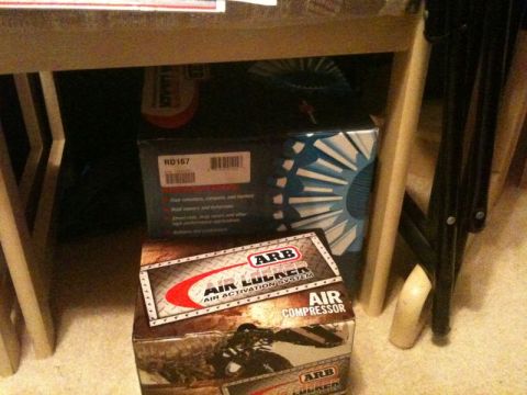 1990 Ford F-250 - Two ARB air locker boxes are stacked under a table. The top box is dark blue with a white and blue fan-like graphic and the text "RD167". T…