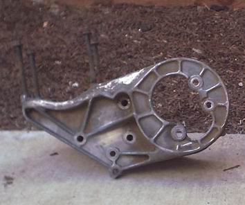 1990 Ford F-250 - This is a metal bracket, likely an engine component, with multiple mounting holes and a circular mounting flange. It is silver in color and…