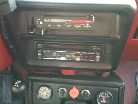 1990 Ford F-250 - The interior of a 1990 Ford F-250 truck shows the center console with a car stereo, climate controls, a 4x4 shifter, and two gauges.