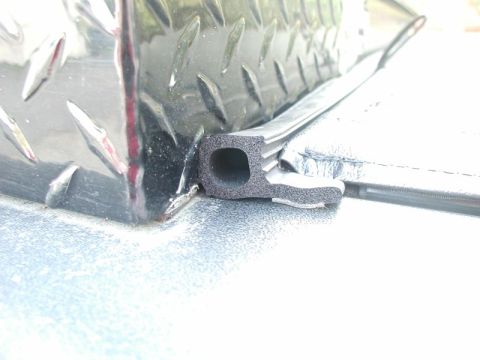 1990 Ford F-250 - A close-up view shows a black rubber seal attached to the edge of a diamond plate toolbox mounted on a truck bed.