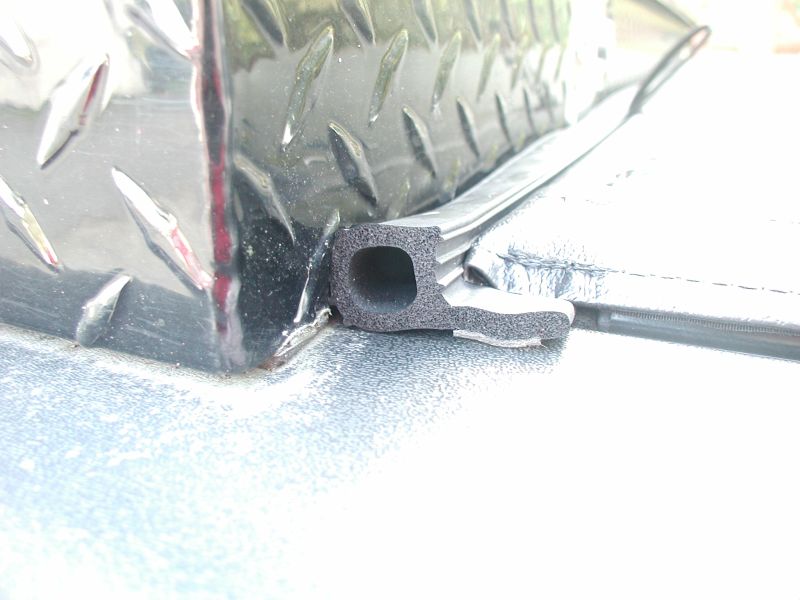 Close-up of black rubber seal on diamond plate toolbox edge on a truck bed.