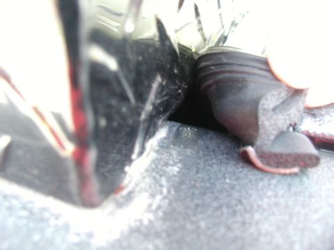 1990 Ford F-250 - A close-up view shows a black rubber seal being compressed between a shiny black surface and a textured gray surface. The seal has a ribbed…