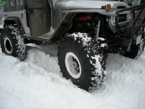 1990 Ford F-250 - A modified Toyota Land Cruiser is shown from the side, partially submerged in deep snow. The vehicle features large, aggressive tires with…