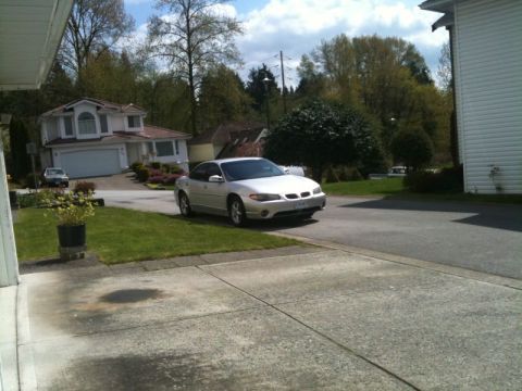2002 Pontiac Grand Prix - A silver 2002 Pontiac Grand Prix is parked on a residential street in front of a house. The car is viewed from the front quarter angle, fac…