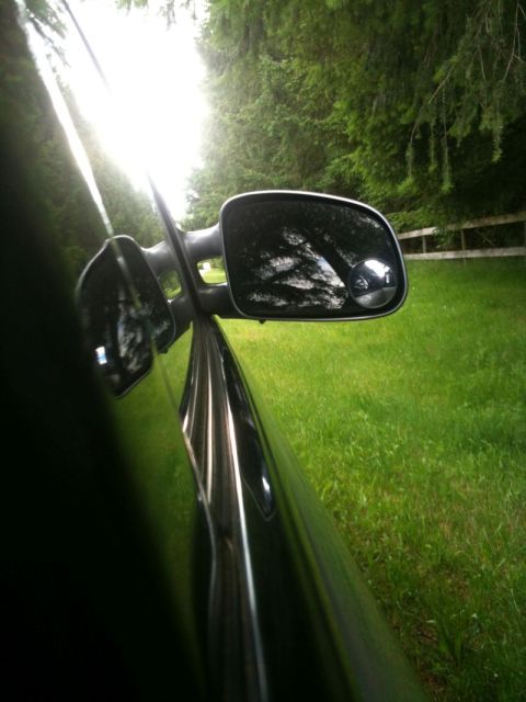 2002 Pontiac Grand Prix - View from the passenger side of a black car, looking out the window and into the side mirror. The side mirror reflects trees and sky, and a…