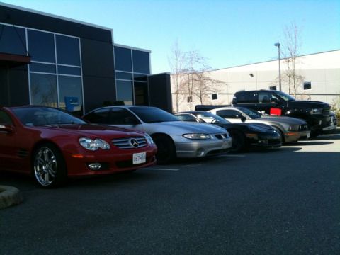 2002 Pontiac Grand Prix - A row of cars are parked in front of a modern building. From left to right, a red Mercedes-Benz SL-Class roadster, a silver Pontiac Grand P…