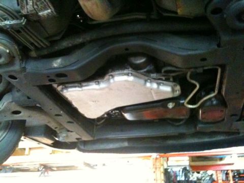 2002 Pontiac Grand Prix - The underside of a vehicle shows the transmission pan and related components. A silver transmission pan is visible, along with a dark-color…