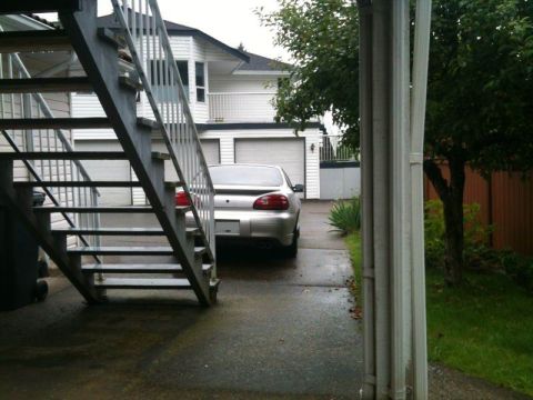 2002 Pontiac Grand Prix - The rear of a silver Pontiac Grand Prix is visible parked in a driveway next to an outdoor staircase. The car is facing away from the camer…