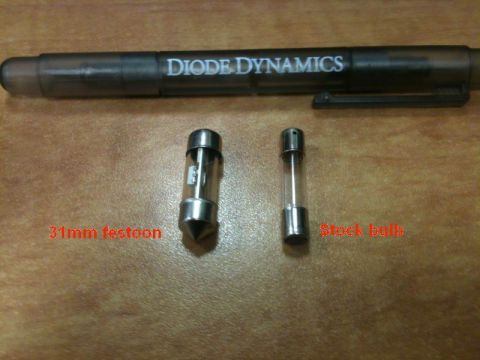 2002 Pontiac Grand Prix - A 31mm festoon bulb is shown next to a stock bulb, with a pen that has "DIODE DYNAMICS" printed on it in the background. The items are plac…
