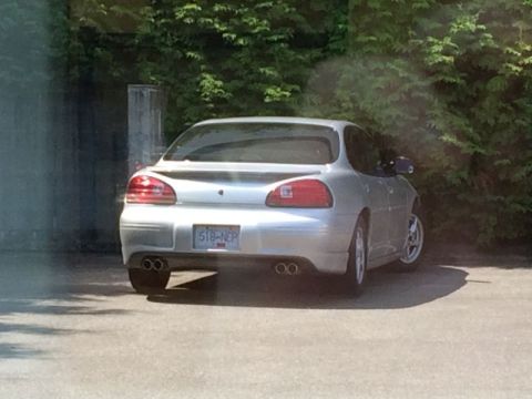 2002 Pontiac Grand Prix - The rear driver's side of a silver Pontiac Grand Prix is shown parked outdoors with a lush green tree line in the background. The car featu…