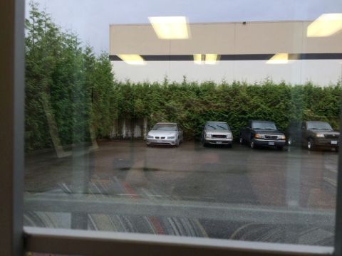 2002 Pontiac Grand Prix - A silver sedan is parked in front of a row of evergreen trees and a building. The parking lot is wet, suggesting it may have rained recentl…