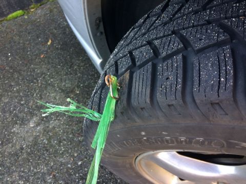 2002 Pontiac Grand Prix - A close-up shot shows a green plastic zip tie that has been used to temporarily plug a puncture in a car tire. The tire tread is visible, a…