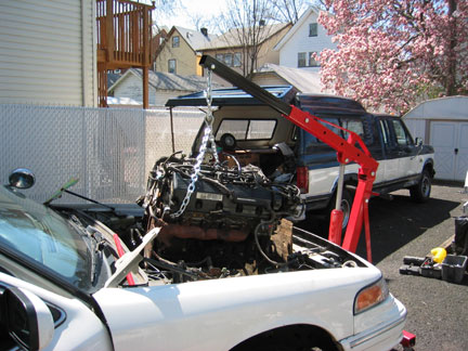 1996 Ford Crown Victoria - Engine removal in progress using an engine hoist, with a second vehicle visible in the background.