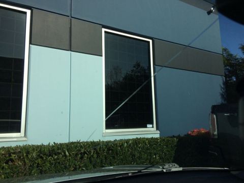 2002 Pontiac Grand Prix - The image shows the exterior of a light blue building with large dark windows and a hedge in front. A portion of a dark-colored vehicle is…