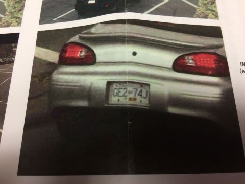 2002 Pontiac Grand Prix - The rear of a silver 2002 Pontiac Grand Prix is shown, featuring its taillights and license plate which reads GE2-74J. The car is parked ou…